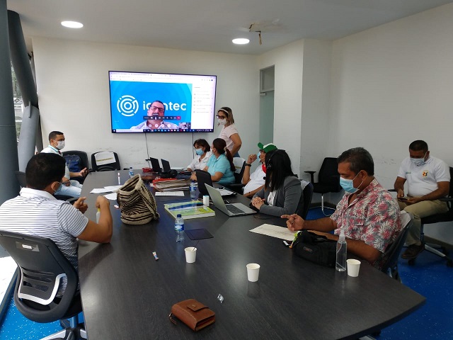 Funcionarios sentados en una sala de reunión con una pantalla que muestra la auditoría virtual de Icontec