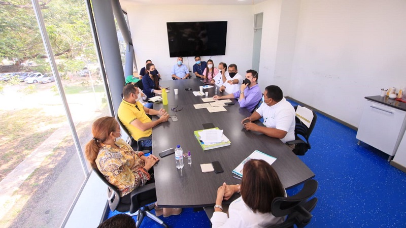 Funcionarios y representantes de empresas de aseo sentados alrededor de una mesa de reunión