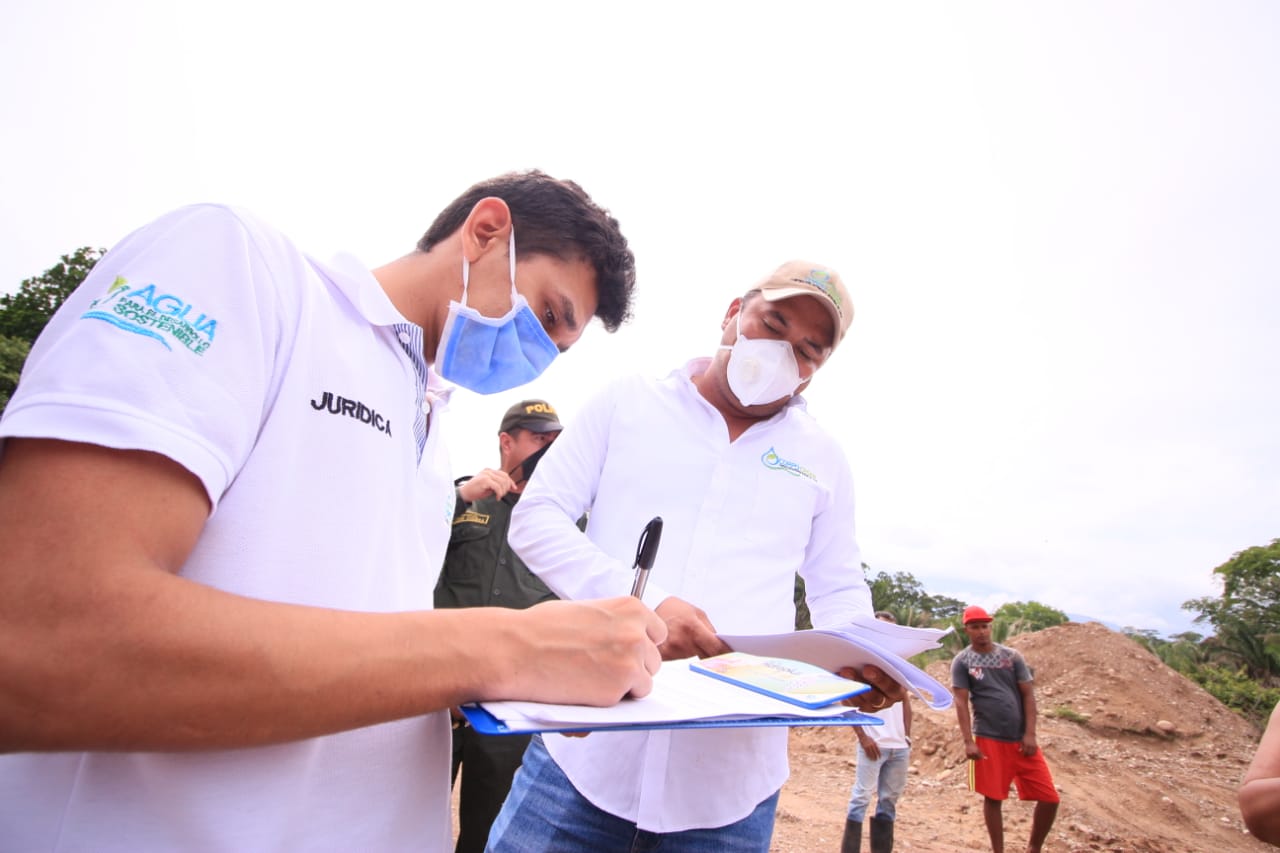 Dos funcionarios con tapabocas firman documentos durante la visita a la zona de extracción