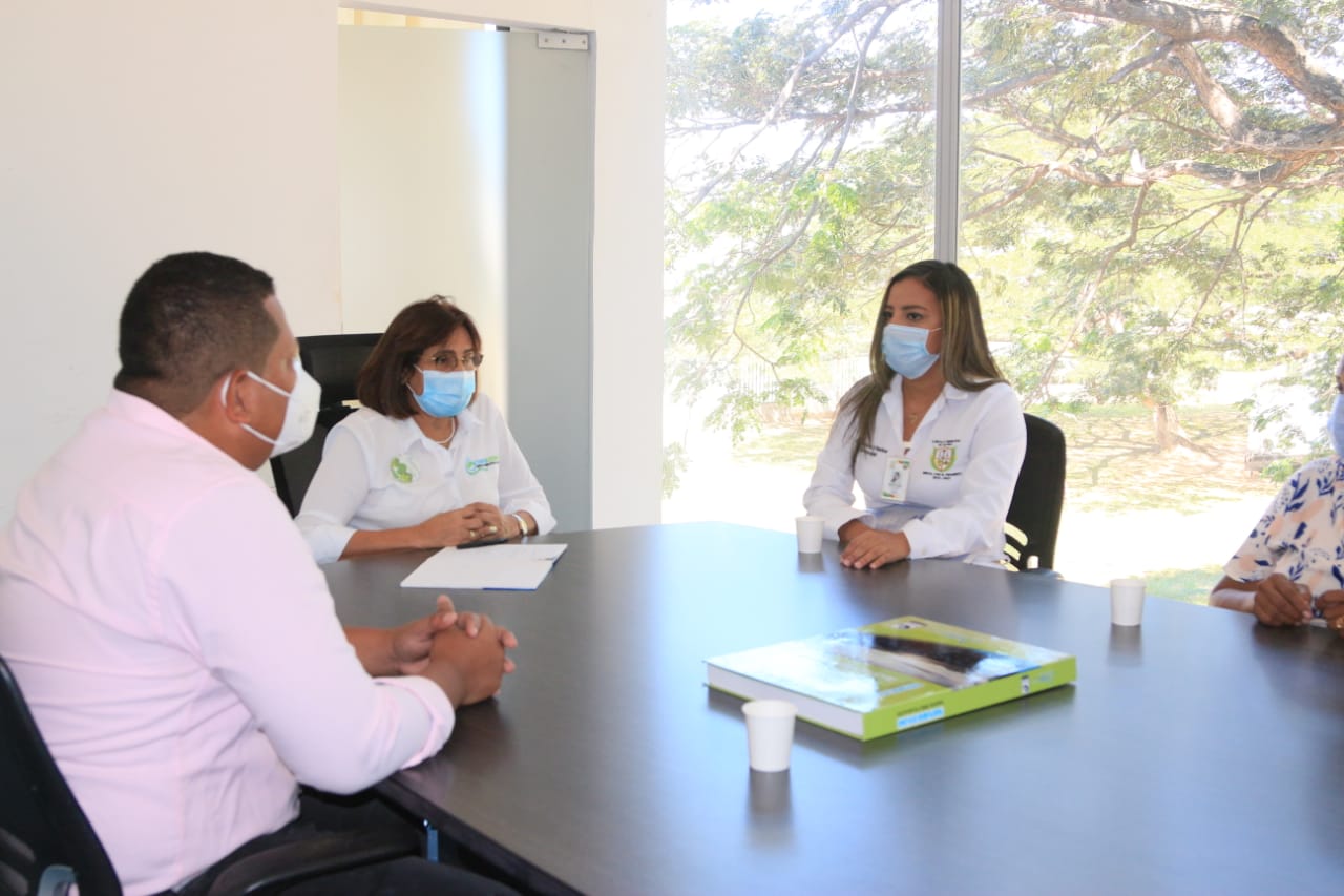 Un funcionario y dos funcionarias con tapabocas reunidos alrededor de una mesa redonda con un concejal