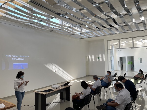 Una funcionaria expone ante los asistentes sentados en un salón amplio con una proyección en la pared