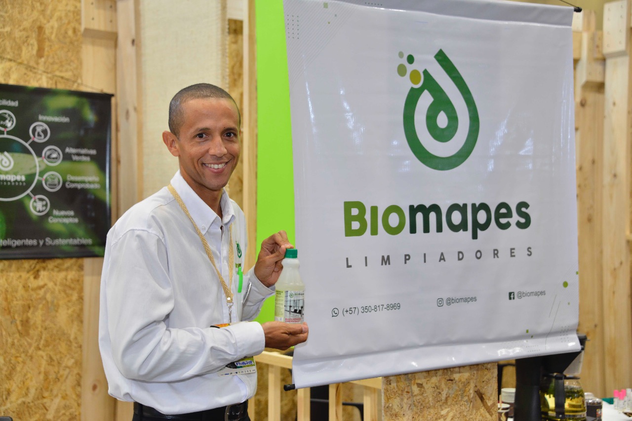 Un emprendedor sonríe junto a un cartel de «Biomapes, limpiadores» en su puesto de la feria Bioexpo.