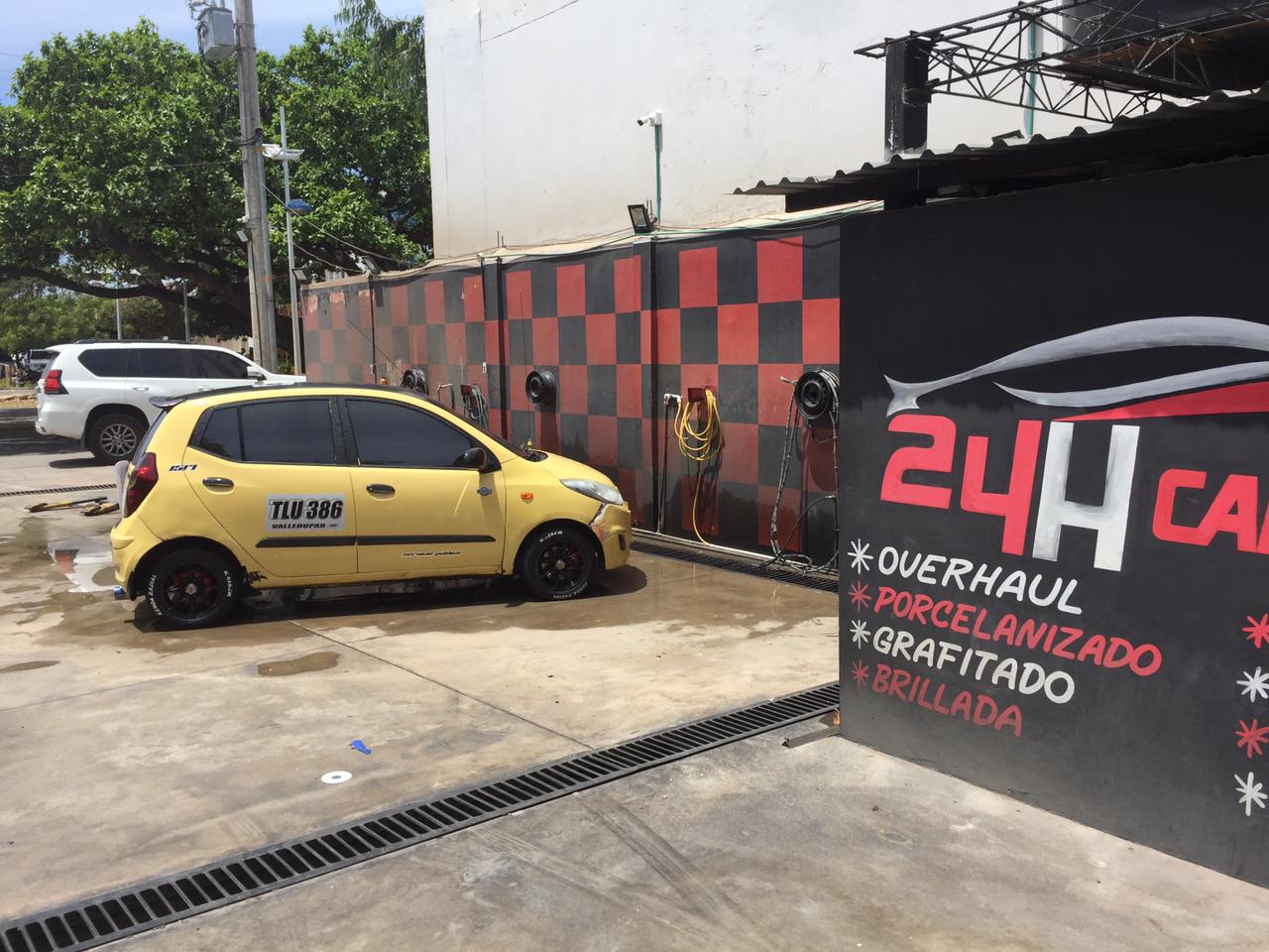 Un taxi amarillo estacionado frente a un establecimiento de lavado de carros con una canaleta al frente