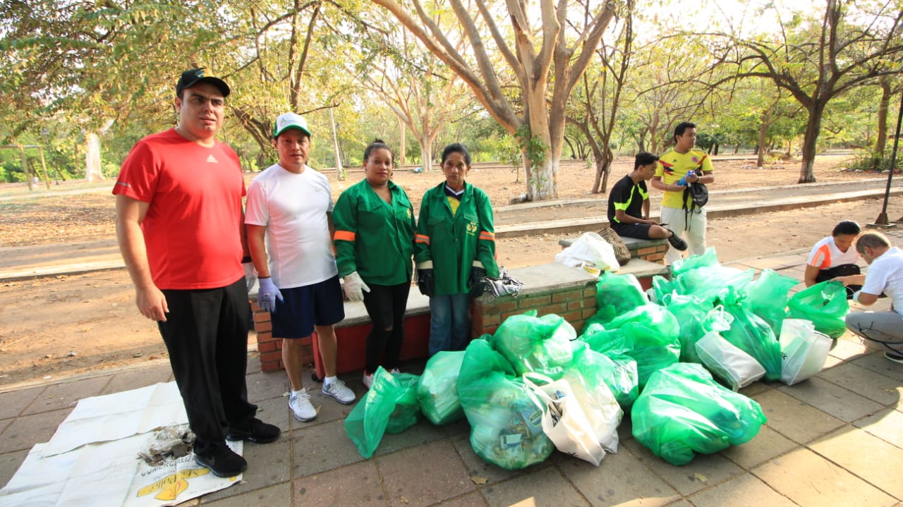 Participantes de la carrera Plugging con bolsas verdes de basura recogida en un parque