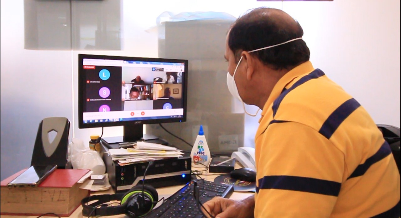 Un funcionario sentado frente a un computador con una videollamada en pantalla durante la capacitación virtual