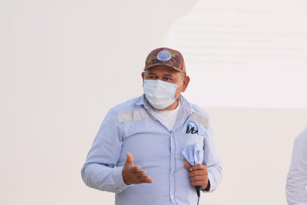 Un funcionario con gorra y tapabocas habla durante la reunión del comité