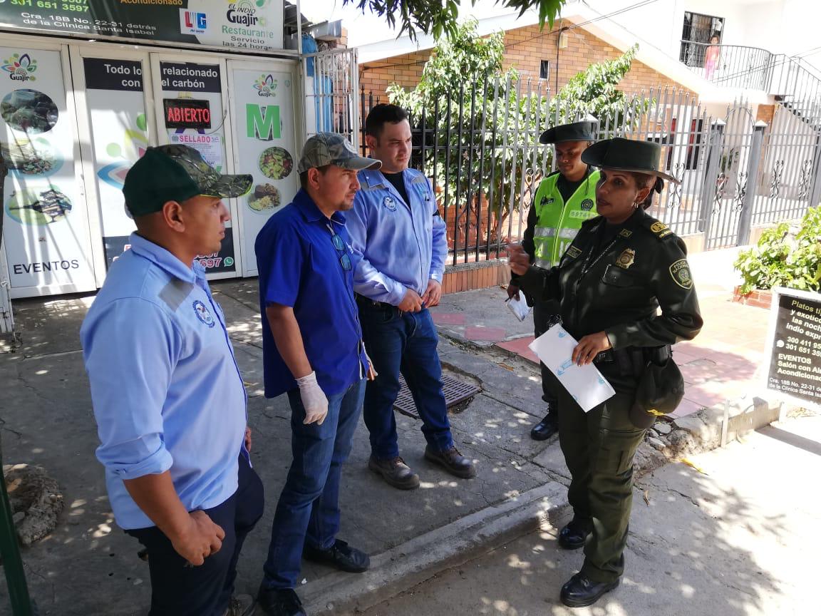 Funcionarios de Corpocesar y policías conversan frente a un restaurante.