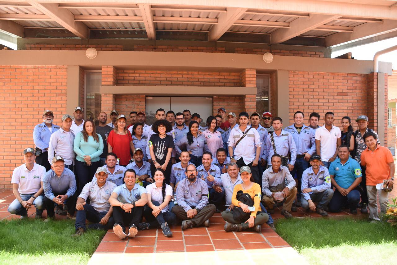 Foto de grupo de los participantes del curso, sentados y de pie sobre el prado frente a la sede.