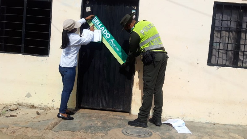 Una funcionaria y un policía colocan un sello de clausura en la puerta de un matadero