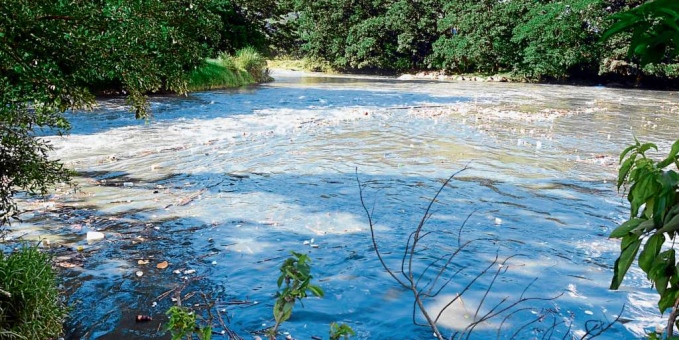 Fotografía del río Casacará: aguas azuladas con espuma y basura flotando entre las orillas.
